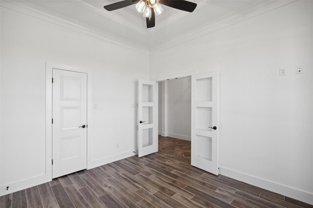 unfurnished bedroom with crown molding, a tray ceiling, dark wood-type flooring, and baseboards