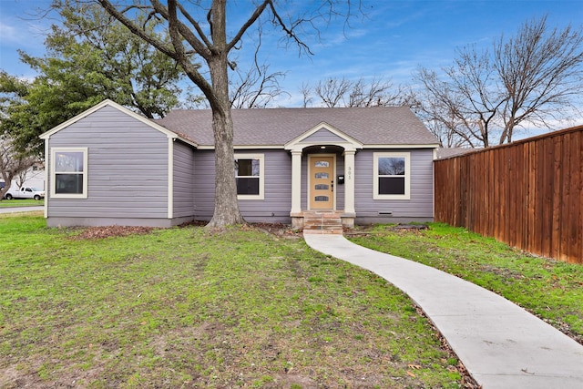 view of front of home with a shingled roof, fence, and a front yard