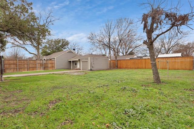 view of yard featuring a garage, driveway, and a fenced backyard