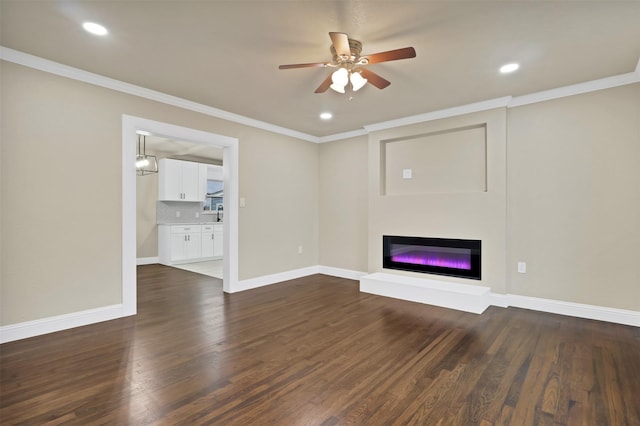 unfurnished living room featuring dark wood-style floors, a glass covered fireplace, crown molding, and baseboards