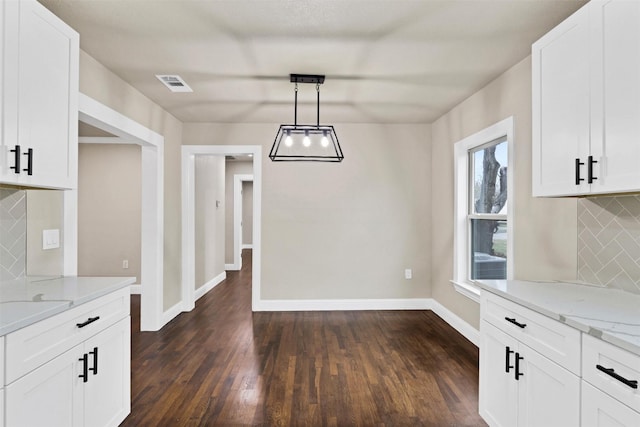 unfurnished dining area with dark wood finished floors, visible vents, and baseboards