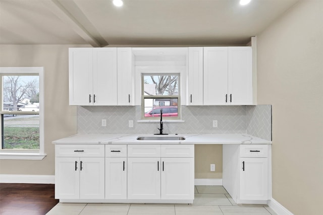 kitchen featuring a wealth of natural light, a sink, and white cabinetry