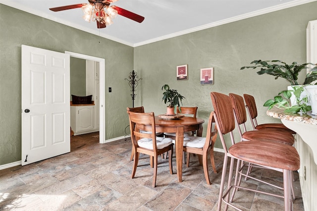 dining room with a textured wall, baseboards, crown molding, and stone tile floors