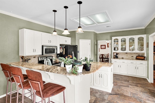 kitchen featuring a breakfast bar, stainless steel appliances, glass insert cabinets, white cabinetry, and a peninsula