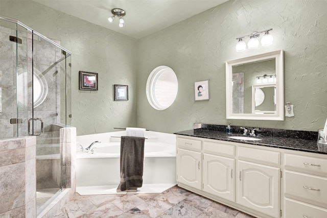 bathroom featuring a textured wall, a garden tub, vanity, and a shower stall