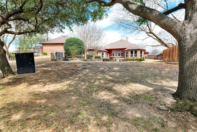 rear view of property featuring brick siding, a chimney, and fence