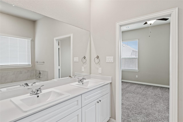 full bath with double vanity, a ceiling fan, and a sink