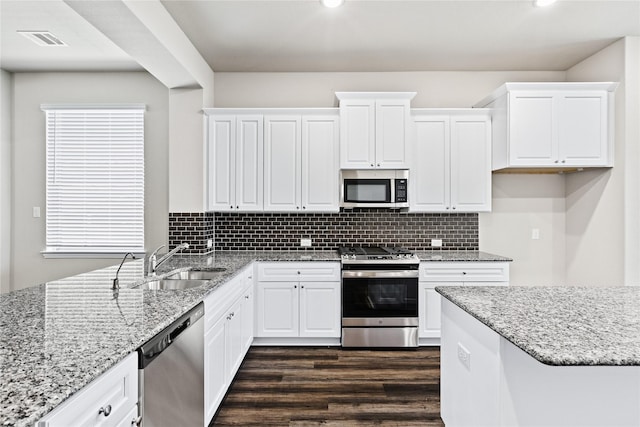 kitchen featuring tasteful backsplash, visible vents, dark wood-style floors, stainless steel appliances, and a sink