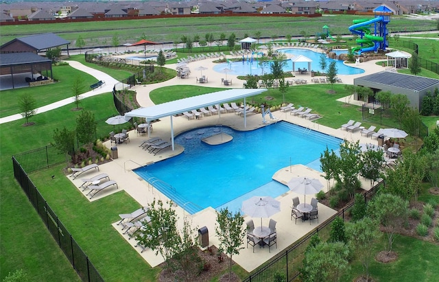 pool featuring a water slide, fence, a water play area, a residential view, and a patio area