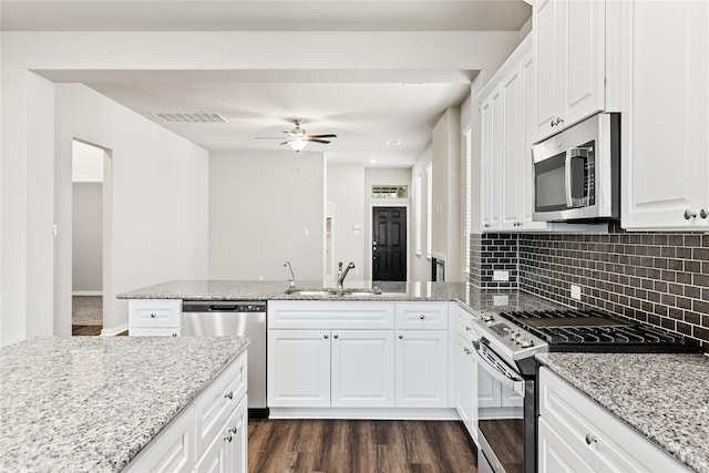 kitchen with visible vents, dark wood-style flooring, a peninsula, stainless steel appliances, and a sink