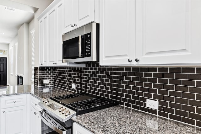 kitchen with appliances with stainless steel finishes, backsplash, visible vents, and white cabinets