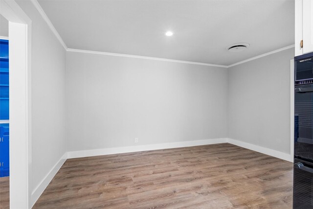 spare room with visible vents, baseboards, wood finished floors, and crown molding