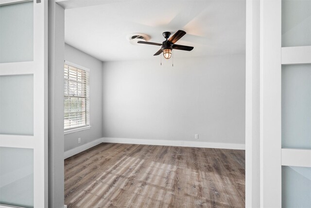 spare room with wood finished floors, baseboards, visible vents, and ceiling fan