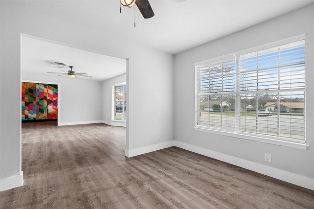 unfurnished room with ceiling fan, visible vents, baseboards, and wood finished floors