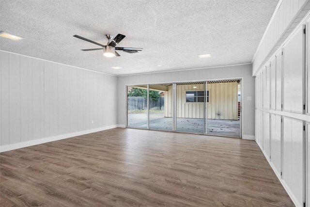 interior space featuring baseboards, a ceiling fan, wood finished floors, and crown molding