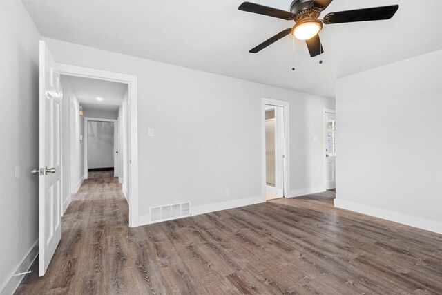 spare room with visible vents, a ceiling fan, baseboards, and wood finished floors