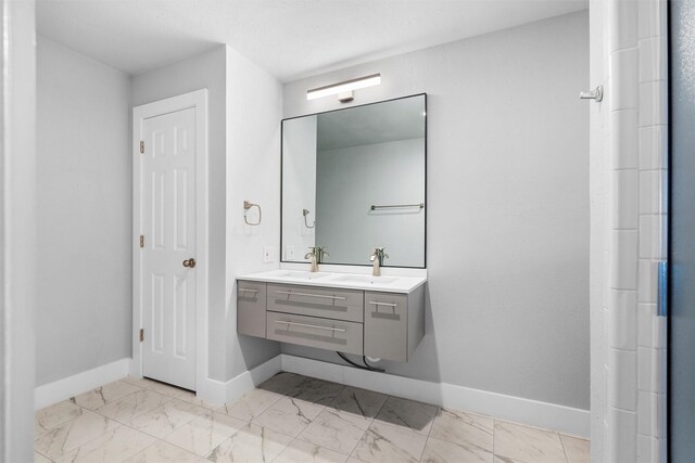 full bathroom featuring marble finish floor, baseboards, and a sink