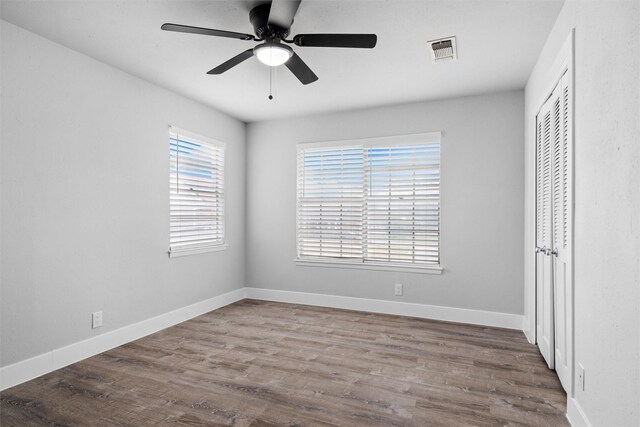 unfurnished bedroom featuring visible vents, baseboards, wood finished floors, a closet, and a ceiling fan