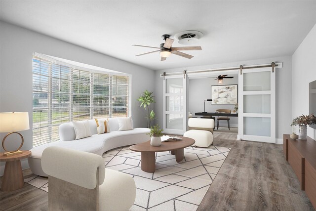 living room featuring visible vents, ceiling fan, a barn door, and wood finished floors