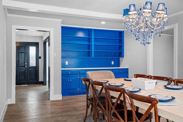 dining area featuring wood finished floors, visible vents, baseboards, an inviting chandelier, and crown molding