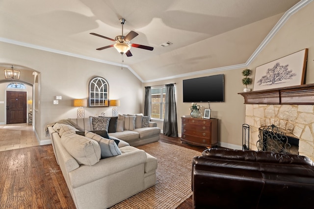 living area featuring ornamental molding, arched walkways, vaulted ceiling, and wood finished floors