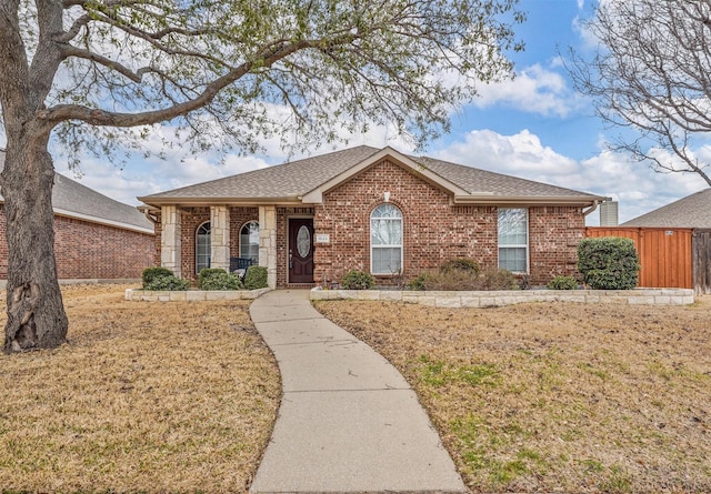 single story home featuring a shingled roof, brick siding, fence, and a front lawn