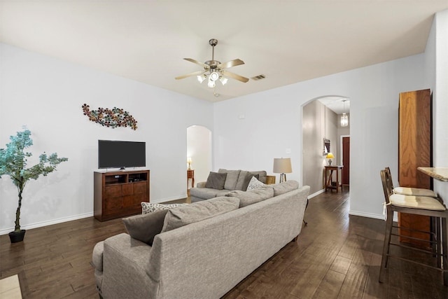 living room with dark wood-style floors, arched walkways, visible vents, a ceiling fan, and baseboards