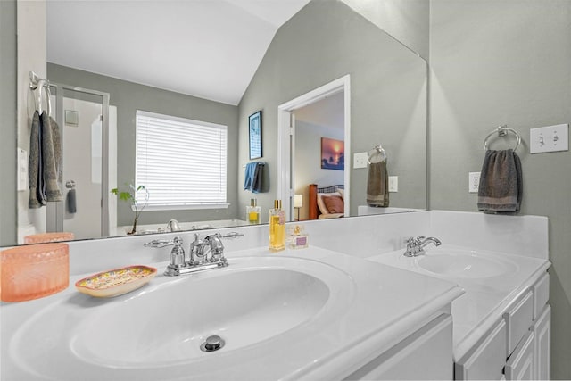 bathroom featuring vaulted ceiling, double vanity, a sink, and a shower with door