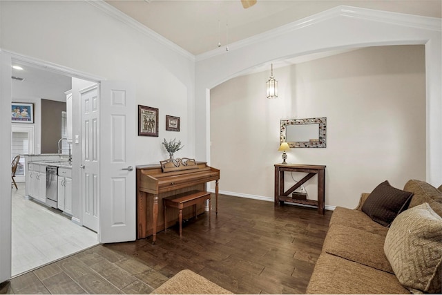 living room with arched walkways, wood finished floors, a ceiling fan, baseboards, and ornamental molding