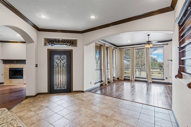 entrance foyer with light wood-style floors, baseboards, ornamental molding, and a textured ceiling