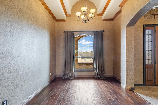 foyer with arched walkways, a chandelier, baseboards, ornamental molding, and dark wood finished floors