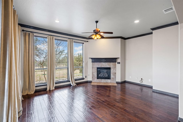 unfurnished living room with crown molding, dark wood-style flooring, a fireplace, and a healthy amount of sunlight