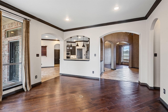 empty room featuring crown molding, baseboards, and hardwood / wood-style flooring