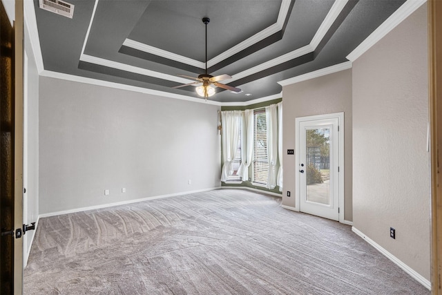 spare room featuring carpet floors, a tray ceiling, crown molding, visible vents, and baseboards