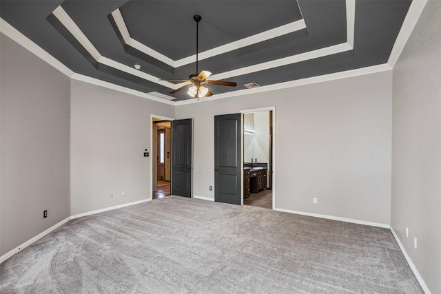 unfurnished bedroom with ornamental molding, a raised ceiling, and baseboards