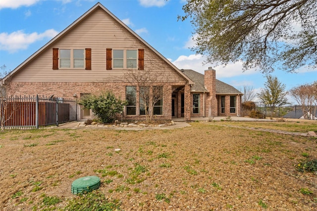 back of property with a chimney, fence, a lawn, and brick siding