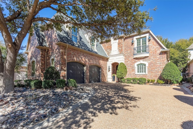 view of front of home with brick siding, a balcony, a garage, a high end roof, and driveway