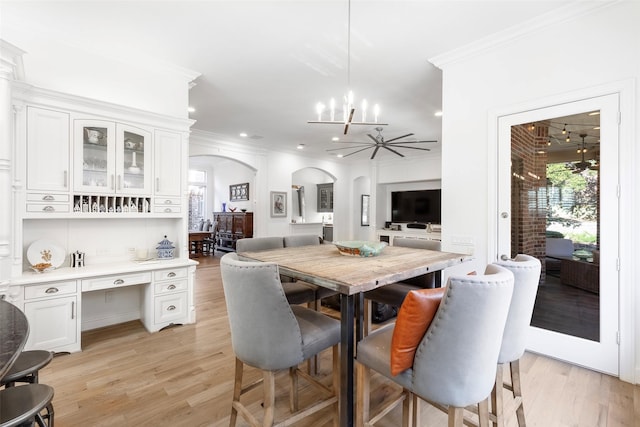 dining room featuring arched walkways, light wood finished floors, a healthy amount of sunlight, and crown molding