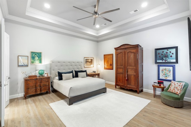 bedroom featuring light wood finished floors, a tray ceiling, and visible vents