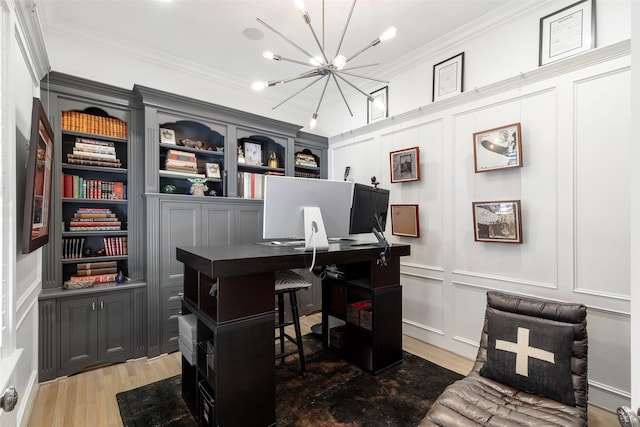 home office featuring ornamental molding, a notable chandelier, a decorative wall, and light wood finished floors