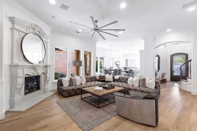 living room with light wood-style floors, a premium fireplace, visible vents, and crown molding