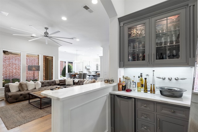 bar with tasteful backsplash, visible vents, arched walkways, light wood-style flooring, and recessed lighting