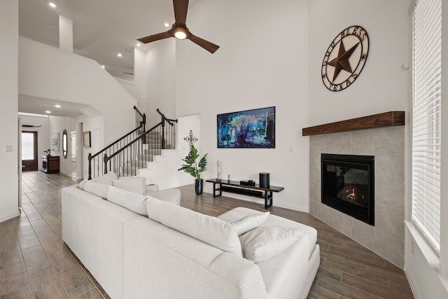 living area with a tile fireplace, recessed lighting, wood finished floors, a ceiling fan, and stairs