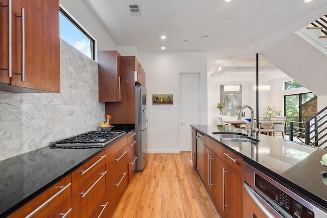 kitchen featuring light wood finished floors, visible vents, backsplash, appliances with stainless steel finishes, and a sink