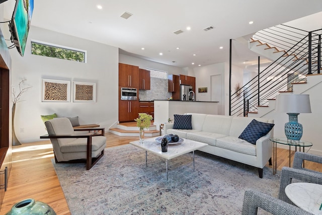 living room with stairway, light wood-type flooring, and recessed lighting