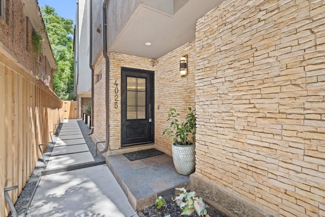doorway to property with brick siding and fence