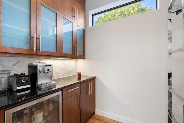 kitchen with wine cooler, backsplash, light wood-style flooring, and glass insert cabinets