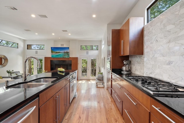 kitchen with visible vents, brown cabinetry, appliances with stainless steel finishes, french doors, and a sink