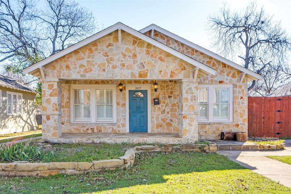 view of front of house featuring stone siding and fence