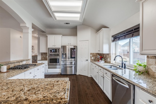 kitchen featuring visible vents, light stone counters, dark wood-type flooring, stainless steel appliances, and a sink